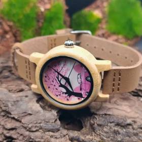 Gros plan sur la montre en bois vintage avec son cadran rose et son bracelet en bois.
