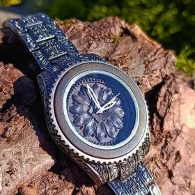 Montre en bois artisanale de luxe Marguerite gravee pose sur une écorce