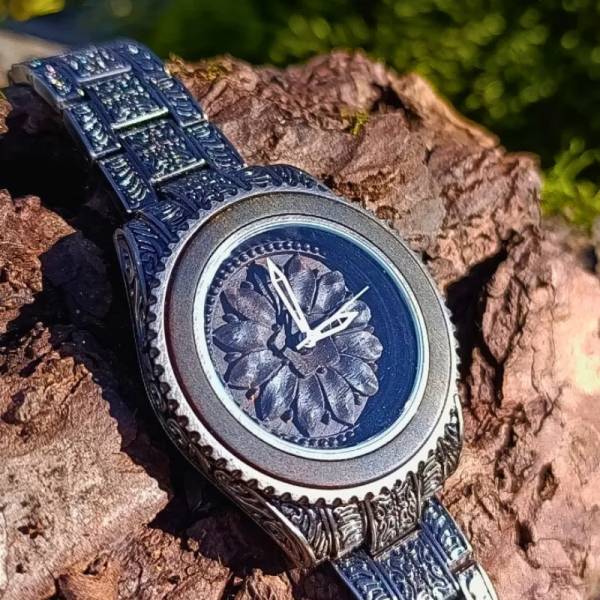 Montre en bois artisanale de luxe Marguerite gravee pose sur une écorce